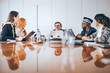 © jaimelafrickmartial  - Five colleagues of different ages sitting around a table in a meeting, multi-ethnic consultants discussing the company's financial strategy.