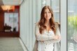 © Maria Vitkovska - Portrait of beautiful smiling businesswoman with arm crossed standing in modern office. Confident manager, worker wearing stylish clothes looking at camera indoors. Successful business, career concept