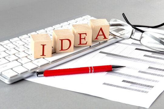IDEA written on a wooden cube on the keyboard with chart on grey background