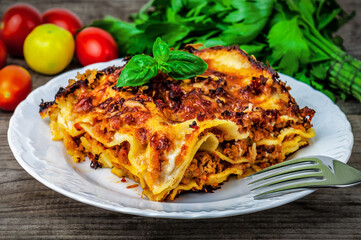 Wall Mural - Italian lasagna with tomato sauce and cheese served with tomatoes and spinach