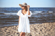 © rogerphoto - Happy blonde woman is posing on the ocean beach with sunglasses and a hat. Evening sun