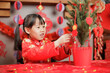 young girl was decorating Chinese New year greeting card against with traditional Chinese 