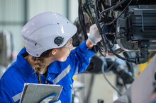 Woman Engineer In Uniform Helmet Inspection Check Control Heavy Machine Robot Arm Construction Installation In Industrial Factory. Technician Worker Check For Repair Maintenance Electronic Operation