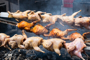 Quails on the rotisserie, street food, grilled poultry