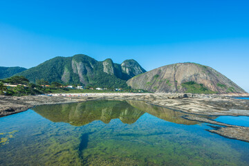 Wall Mural - View of the beautiful Itacoatiara Beach and it's cliff reflected in the water - Niterói, State of Rio de Janeiro, Brazil