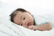 © amorn - Newborn baby sleeping on blanket on white bed. Infant lying on white bed. Asian newborn baby sleeping in prone position. Asian infant