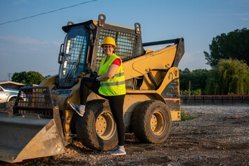 cheerful female excavator operator on construction site. Woman construction apprentice learning to drive heavy equipment