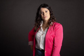 Empowered young woman with pink jacket. Ontological coaching. Feminist. Black background. Isolated