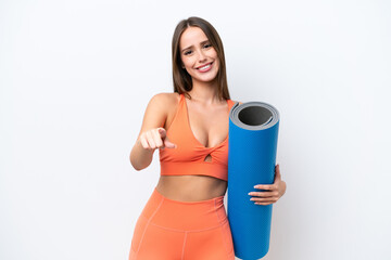 Wall Mural - Young beautiful sport woman going to yoga classes while holding a mat isolated on white background pointing front with happy expression