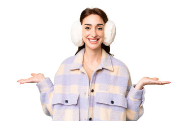 Wall Mural - Young caucasian woman wearing winter muffs over isolated chroma key background with shocked facial expression