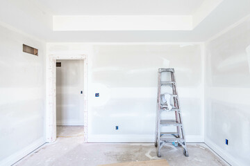 High and dirt ladder put by unfinished drywall on the floor in empty room at construction site. New build property project. Home improvement, house renovation concept. Ready for Interior and paintwork