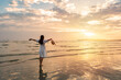 Leinwandbild Motiv Young woman traveler relaxing and enjoying the beautiful sunset on the tranquil beach, Travel on the summer vacation concept