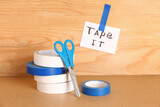 Fototapeta  - Adhesive tape roll and paper with text TAPE IT on wooden background