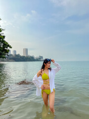 Wall Mural - Sexy asian woman Wear a yellow body suit. Standing in the sea