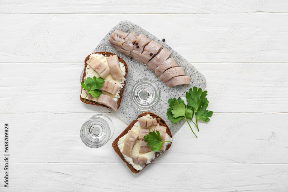 Shots with cold vodka and snacks on white wooden background