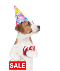 Poster - Jack russell terrier puppy  wearing a party cap holds gift box and shows signboard with labeled 