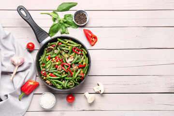 Wall Mural - Frying pan with different vegetables on light wooden background