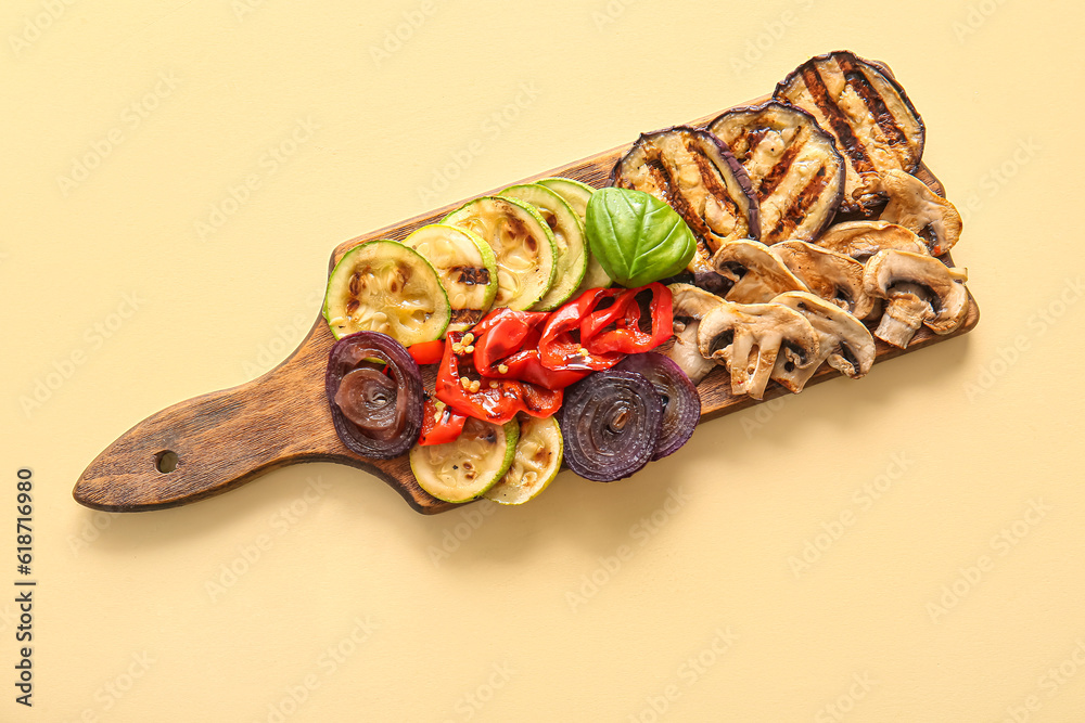 Wooden board with tasty grilled vegetables on yellow background