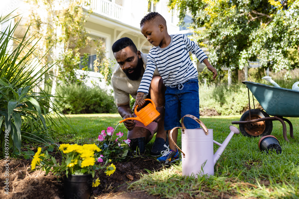 African american father with son watering flower pots and plants in ...