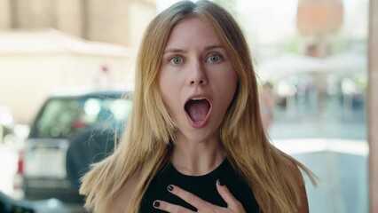 Poster - Young blonde woman standing with surprise expression at street