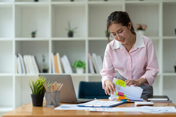 Wall Mural - Asian businesswoman working in piles of paper files Documents in the meeting to search and review the various work folders at the desk to record information. management concept