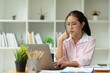 © Phimwilai - Cropped image of asian businesswoman analyzing paperwork using laptop to actively search for information tense expressions at the office.