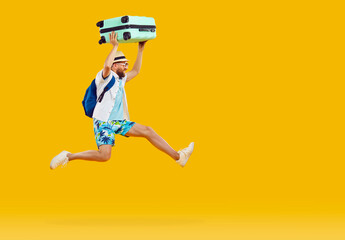 Wall Mural - Funny tourist man in summer shirt and shorts, with suitcase and backpack running and jumping isolated on orange yellow background. Summer, holiday, vacation, traveling, hurrying, rush concept