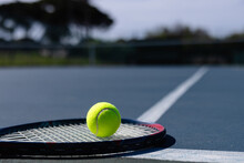 Close Up Of Tennis Ball And Tennis Racket Lying On Tennis Court On Sunny Day, Copy Space