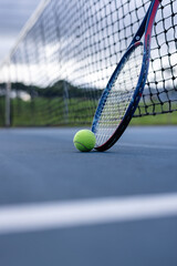 Close up of tennis ball and tennis racket against net on tennis court on cloudy day, copy space