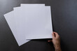 Hand of caucasian woman holding piece of paper over paper pieces with copy space on black background