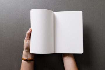 Canvas Print - Hands of caucasian woman holding book with copy space on grey background