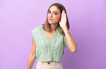 Wall Mural - Young caucasian woman isolated on purple background listening to something by putting hand on the ear