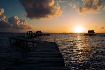 Sticker - Tranquil scene of a lake shoreline at sunset, with a dock stretching out into the water