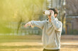 Young college student male model wearing 3D glasses and experiencing virtual reality in an outdoor autumn lawn plaza at a university in South Korea, Asia