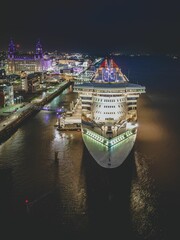 Poster - Illuminated cruise ship docked in a picturesque harbor in the evening.