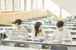 © TEAM PRE-LIGHT - Three young Asian college students, both male and female, are in a classroom in South Korea where they are either teaching or studying