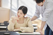 © TEAM PRE-LIGHT - Colleague, friend, motivator, young male model comforting a distressed young female college student model sitting at a desk in a university classroom in Asia Korea.