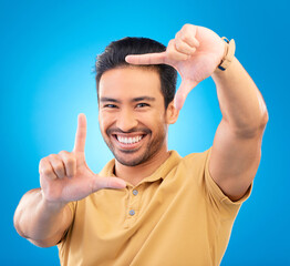 Poster - Portrait, finger frame and man in studio, blue background and review profile picture. Face, happy asian model and hands for planning perspective of photography, selfie and inspiration of photographer