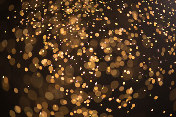 Wall Mural - golden sparks, christmas and new year floating littering stars on black bokeh background, backdrop w