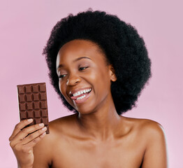 Poster - Black woman, chocolate and diet with candy and beauty, health and dessert snack isolated on pink background. Skin, glow and happy female model with cacao sweets, calories and cosmetics in studio