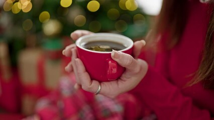 Sticker - Young hispanic woman holding cup of coffee celebrating christmas at home