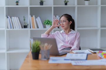 Sharing good business news. Attractive young businesswoman talking on the mobile phone and smiling while sitting at her working place in office and looking at laptop PC.