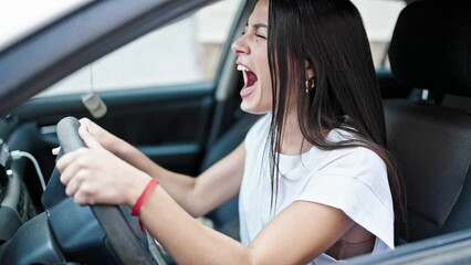 Wall Mural - Young beautiful hispanic woman stressed driving car screaming at street