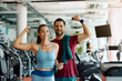 © Drazen - Happy athletic couple flexing their muscles after working out in gym and looking at camera.
