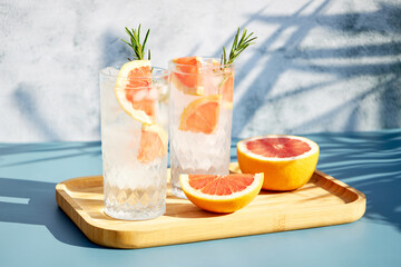 Wall Mural - Summer chilled grapefruit cocktail with ice and rosemary sprig. Summer cold drinks. Soda with citrus