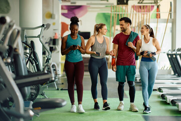 Wall Mural - Happy athletic friends communicating after sports training in gym.