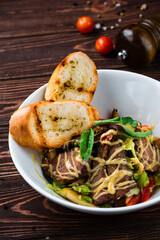 Wall Mural - Meat salad with beef slices, sweet pepper, lettuce, greens and fried toasts in a plate.