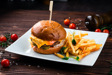 Wall Mural - Beef burger with tomato, pickles cucumber, red onion, lettuce, cheddar cheese, ketchup and French fries, American food.