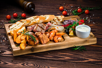 Canvas Print - Seafood board fried shrimps, squid, tuna, salmon fillet, rustic fried potato wedges, onions, lettuce, chili peppers, toasts and sauce.