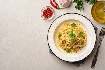 Wall Mural - Spaghetti aglio e olio. Traditional Italian pasta with garlic, olive oil and chili peppers in plate on concrete background.